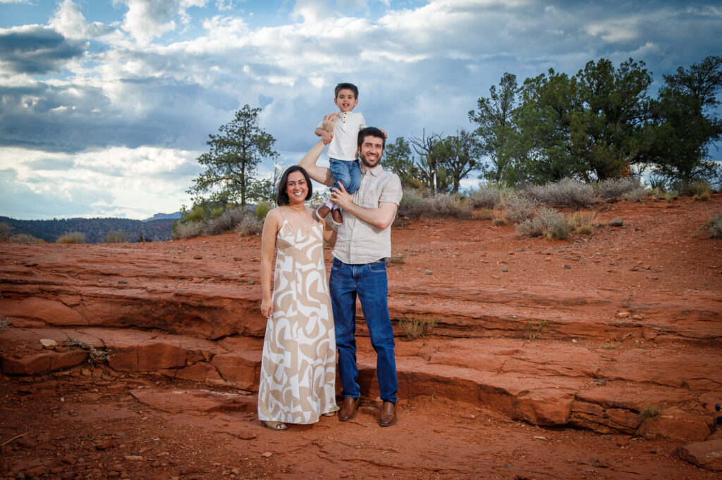 Example Alt Text: Family of three laughing during their sunset anniversary photo session on Secret Slick Rock Trail in Sedona, Arizona