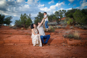 Example Alt Text: Family of three laughing during their sunset anniversary photo session on Secret Slick Rock Trail in Sedona, Arizona