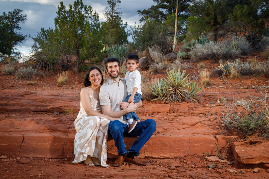 Example Alt Text: Family of three laughing during their sunset anniversary photo session on Secret Slick Rock Trail in Sedona, Arizona