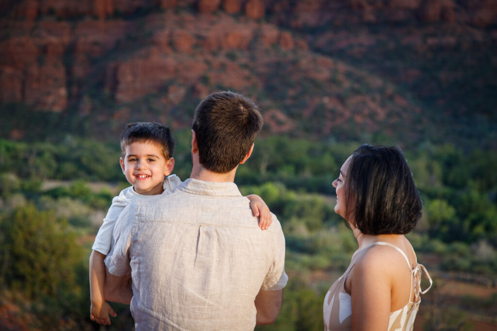 Example Alt Text: Family of three laughing during their sunset anniversary photo session on Secret Slick Rock Trail in Sedona, Arizona