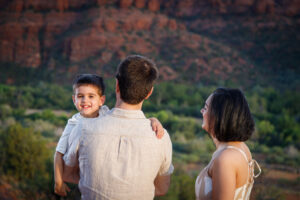 Example Alt Text: Family of three laughing during their sunset anniversary photo session on Secret Slick Rock Trail in Sedona, Arizona