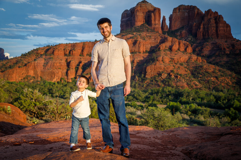 Example Alt Text: Family of three laughing during their sunset anniversary photo session on Secret Slick Rock Trail in Sedona, Arizona